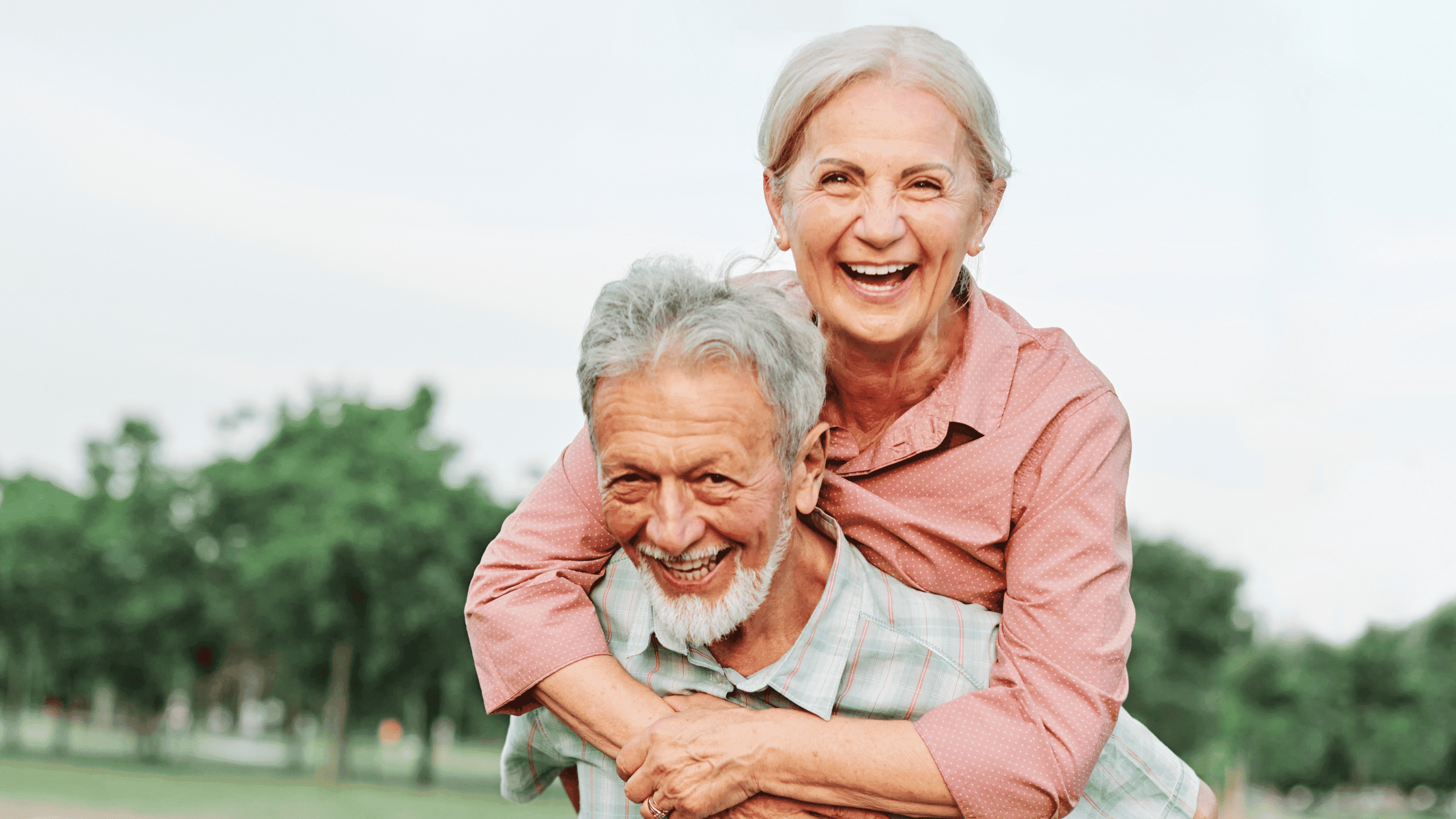 Pareja de adultos mayores sonriendo al aire libre tras comparar planes de Medicare