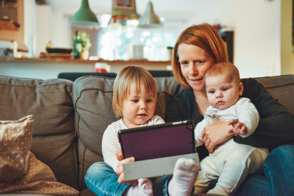 Young mother at home with her baby and toddler thinking about life insurance
