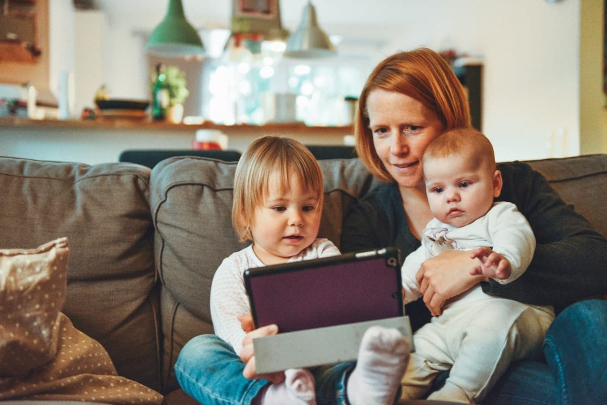 Young mother at home with her baby and toddler thinking about life insurance