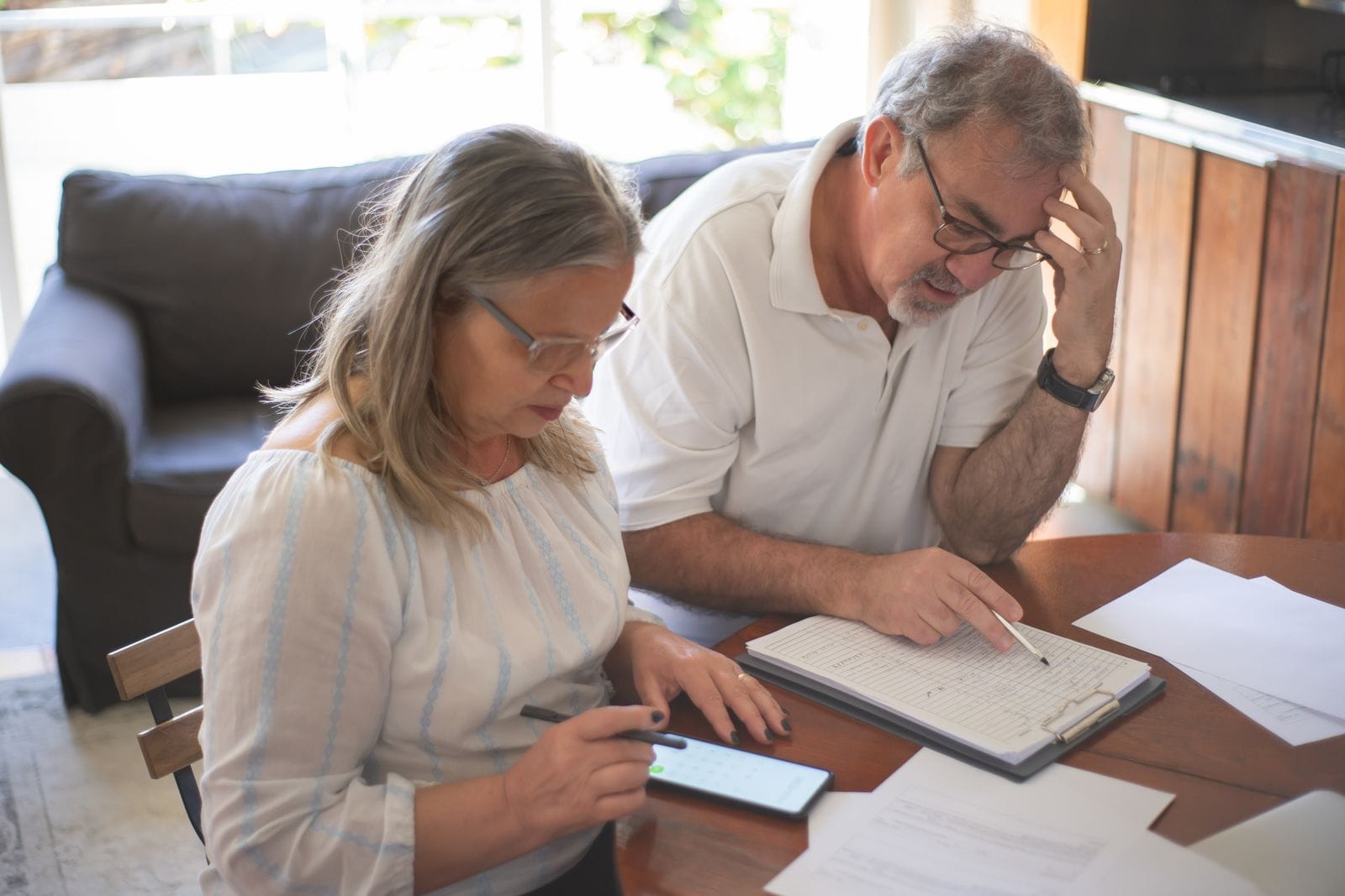 Pareja mayor revisando documentos de Medicare y su ventana de inscripcion en casa